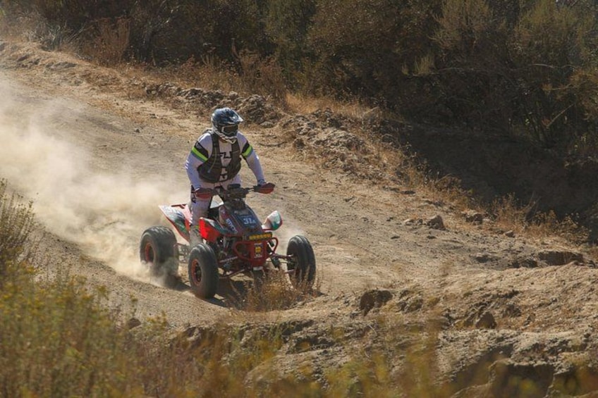 A person riding a quad bike on a dirt trail. 3
