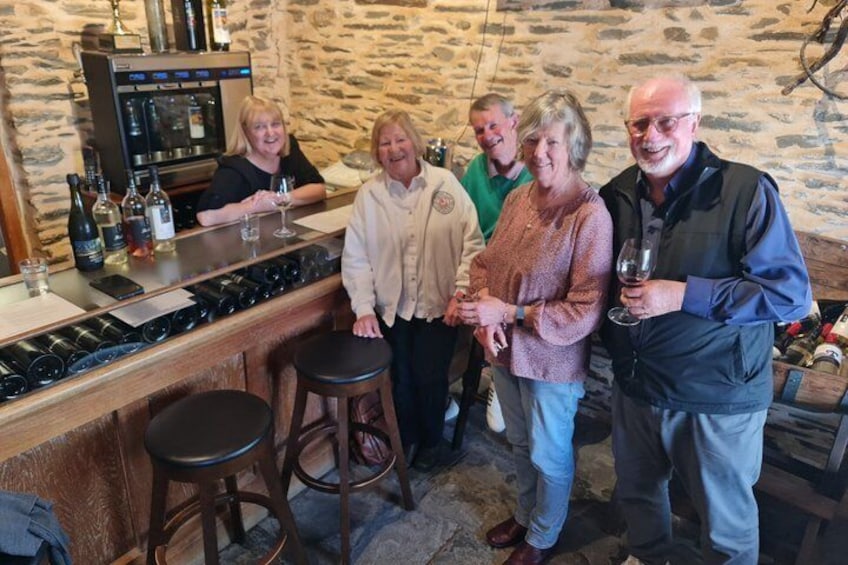 A group of people at a bar with wine bottles and glasses. 2