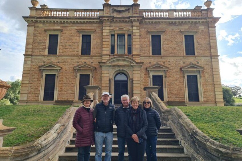 A group of people standing in front of a large, historic building with a grand staircase. 3