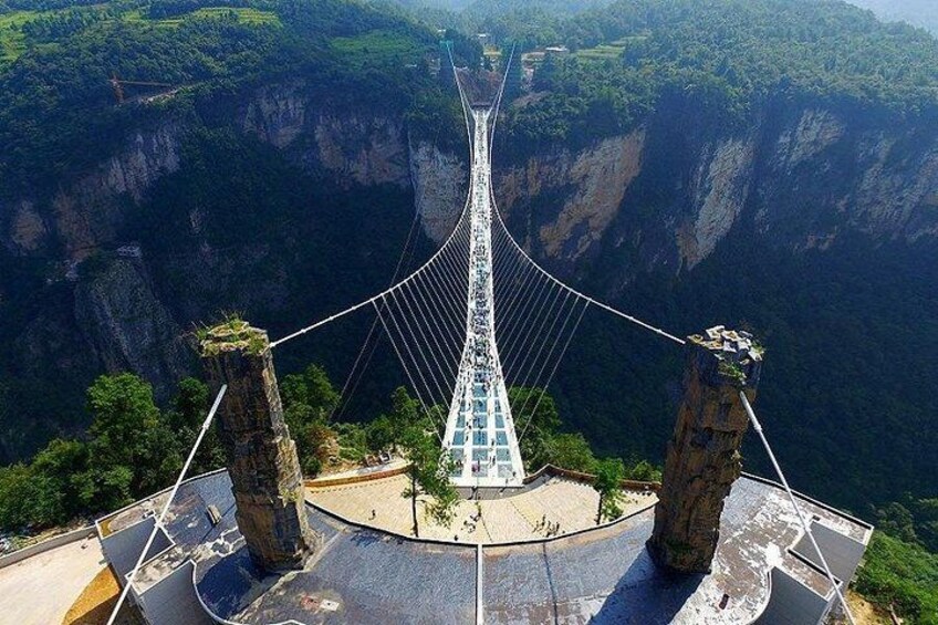 A suspension bridge with a glass walkway, surrounded by steep cliffs and lush greenery. 2