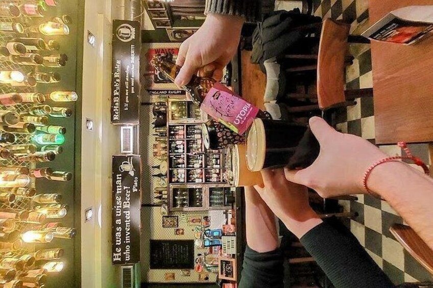 Une personne tenant une tasse rose, une autre personne tenant une tasse noire, et une vitrine présentant diverses bouteilles et différents articles dans un magasin. 4
