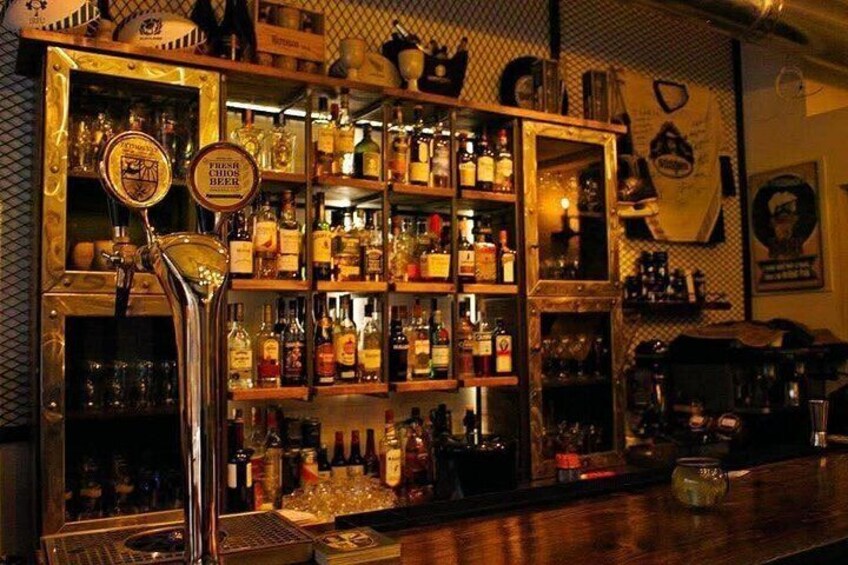 Un bar avec un robinet à bière, des étagères remplies de bouteilles d’alcool et un vieux juke-box. 5