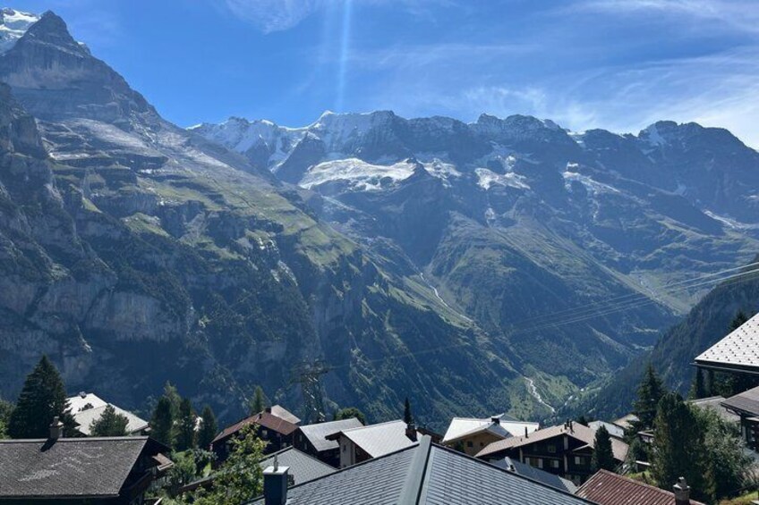 Un paysage montagneux aux sommets enneigés, une vallée parsemée de bâtiments et un ciel dégagé. 3