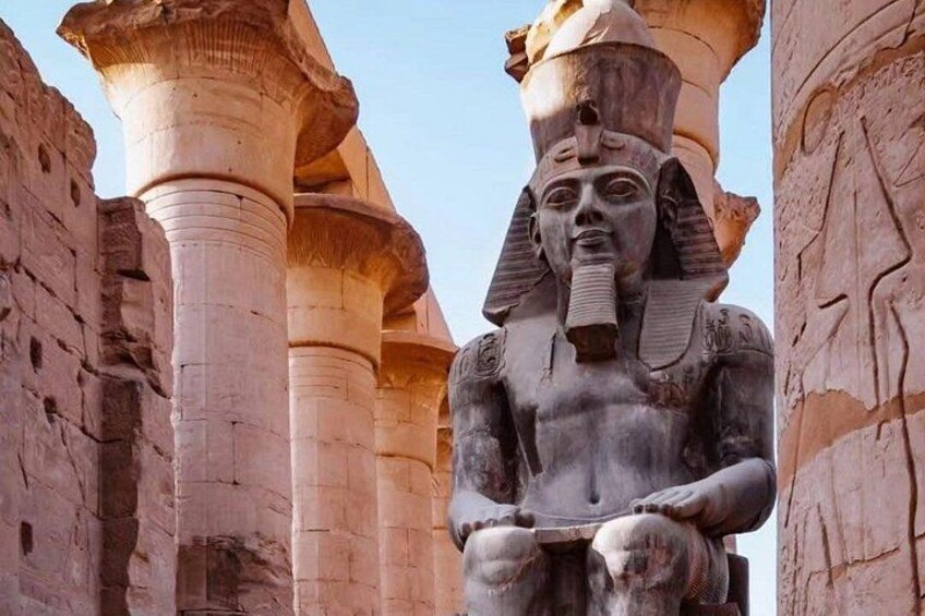 A large stone statue of a seated figure with a headdress, flanked by columns in a historical setting. 3