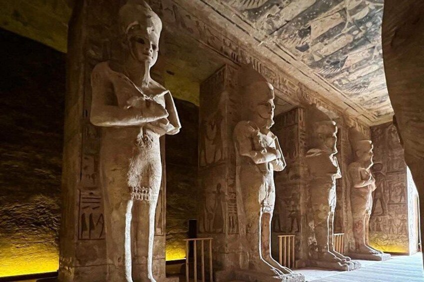 Ancient Egyptian statues in a temple with hieroglyphs on the walls. 1