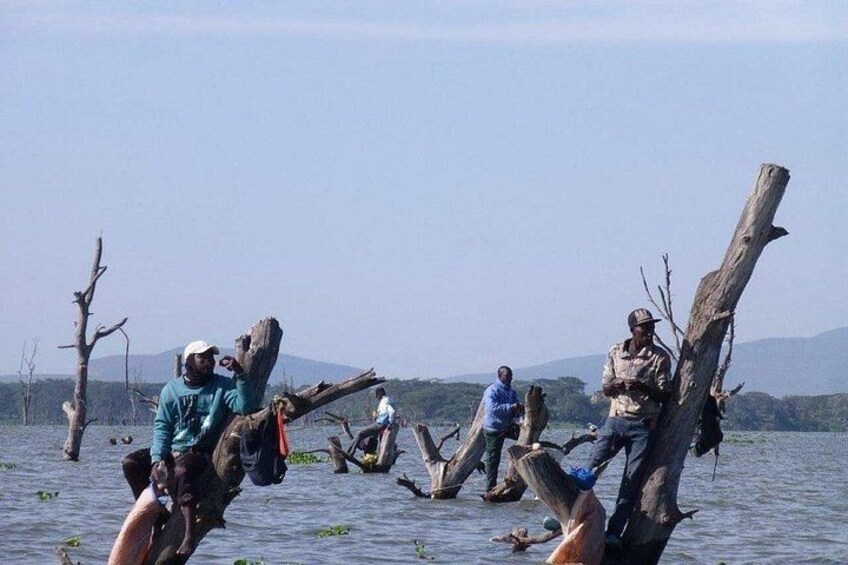 Menschen in einem Boot auf dem Wasser, Bäume im Hintergrund. 2