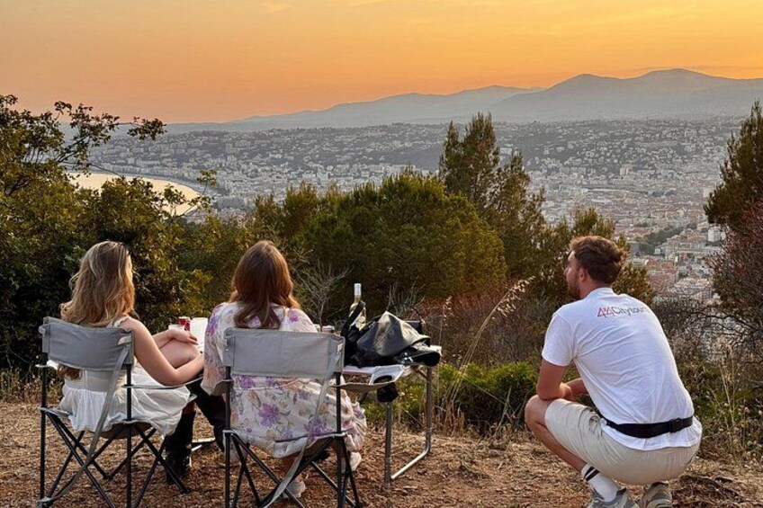 Three people sitting on chairs overlooking a cityscape with mountains in the distance. 2