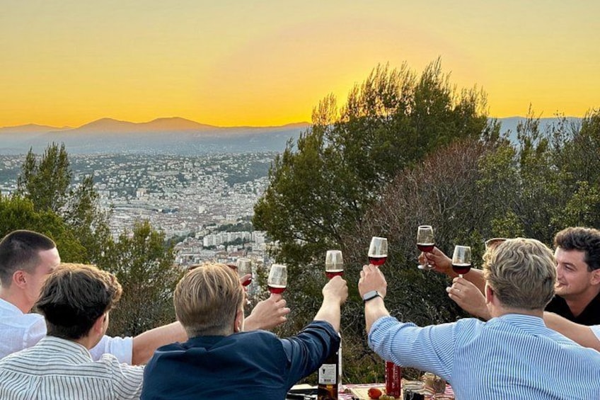 A group of people toasting with wine glasses, overlooking a cityscape with mountains in the background. 1