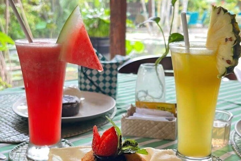 Two drinks on a table with a tropical setting. 5