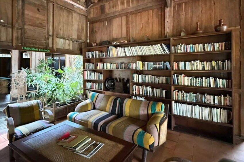 A wooden room with a striped sofa, a coffee table, and bookshelves filled with books. 3