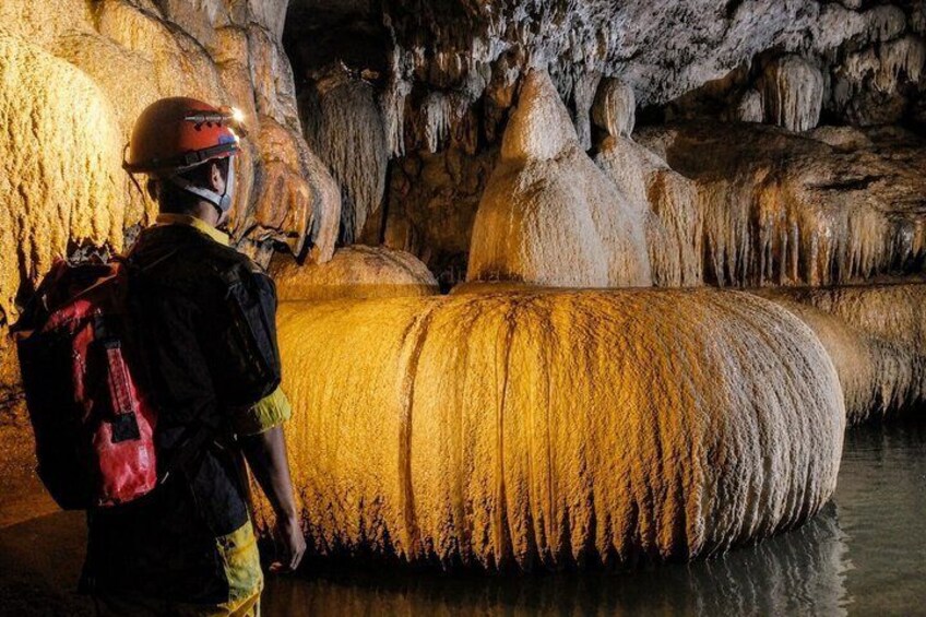 A person standing in a cave with stalactites and stalagmites. 2