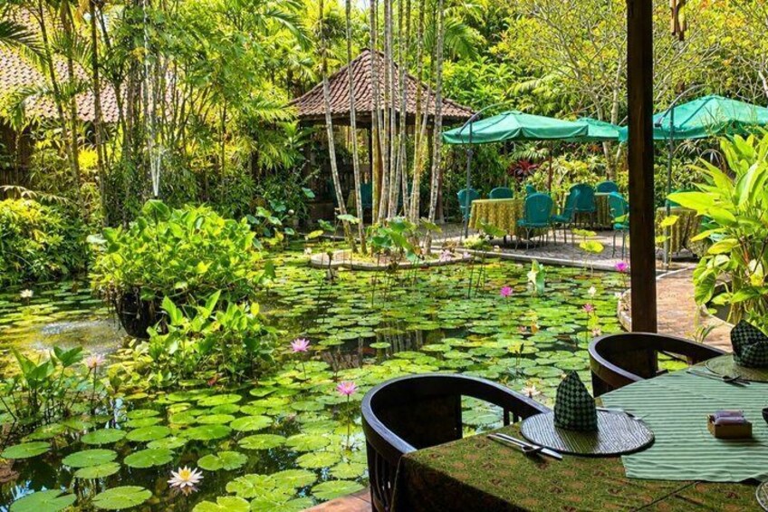 A serene garden with a pond, lush greenery, and outdoor seating. 4