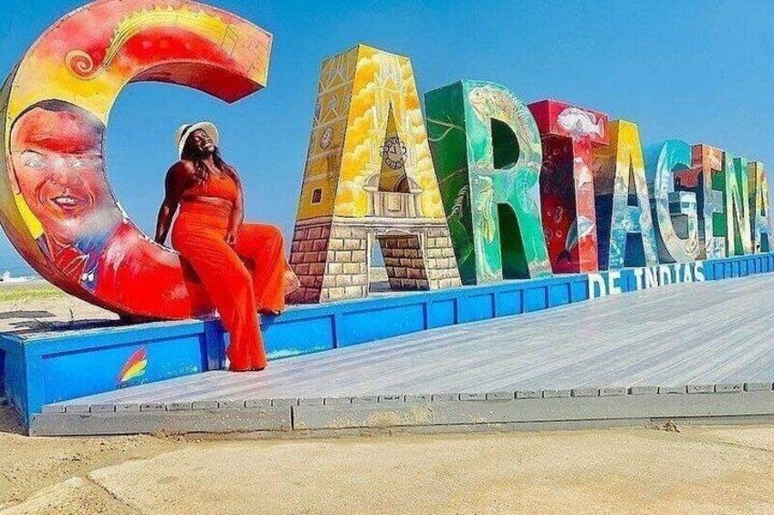 A colorful sign with the word 'CARTAGENA' and a woman in red posing in front of it. 2
