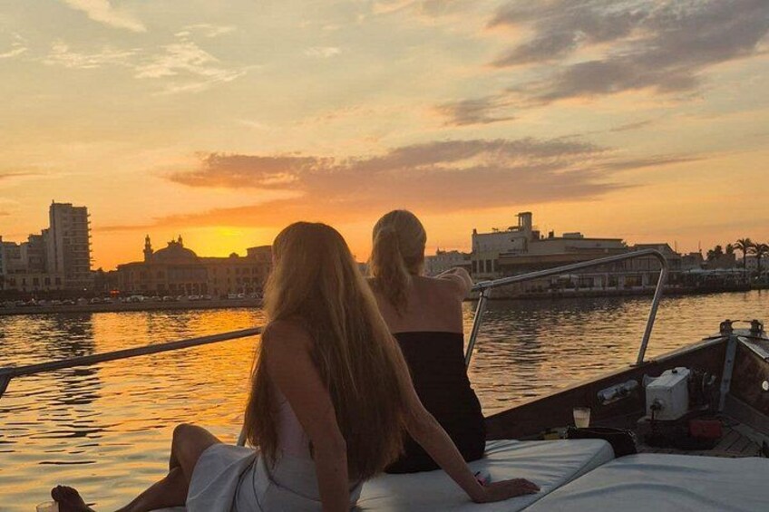 Dos personas sentadas en un bote, observando el horizonte de una ciudad al atardecer. 2