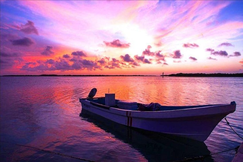 A boat on calm water during sunset with a colorful sky. 2