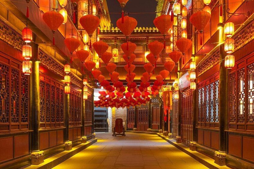 Een gang met traditionele architectuur, rode lantaarns en verlichte ramen. 1