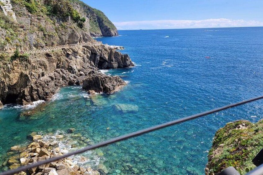 A coastal landscape with clear blue waters, rocky cliffs, and a bridge. 2