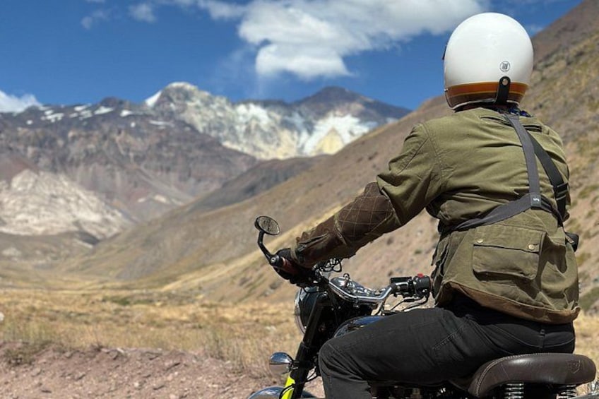 A person riding a motorcycle on a dirt road with mountains in the background. 5