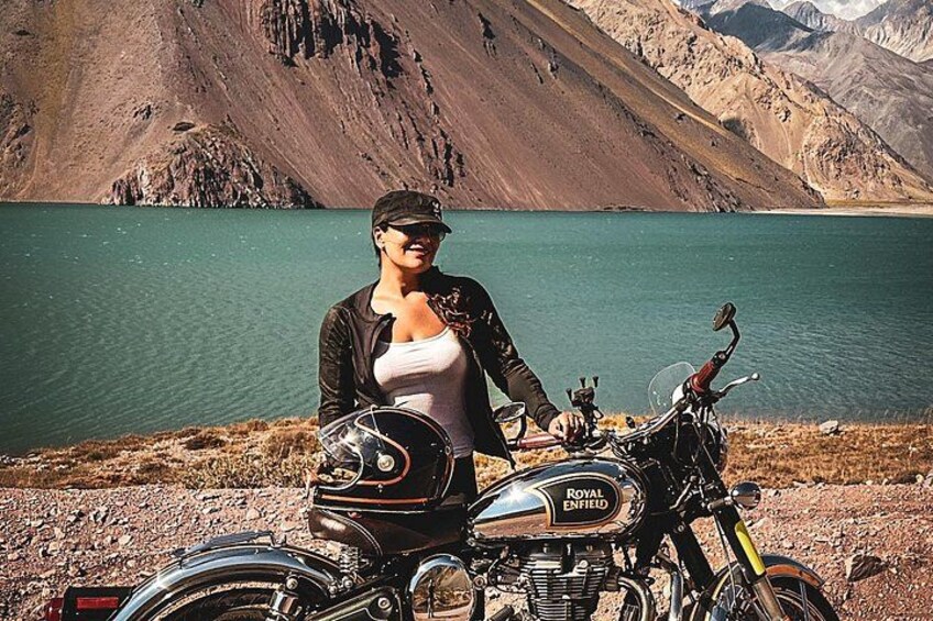 A person standing next to a motorcycle with a mountainous landscape in the background. 2