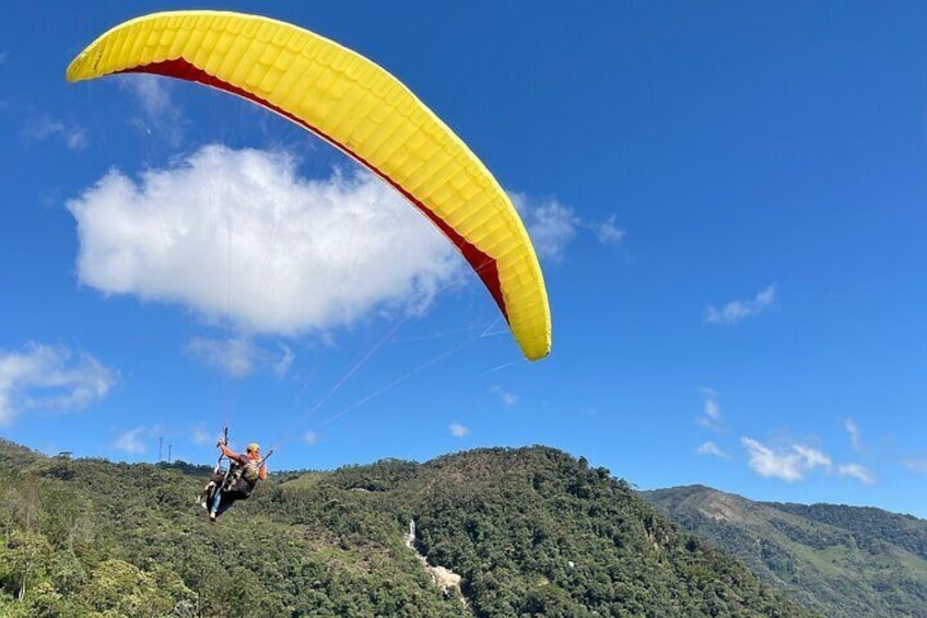 A paraglider with a yellow and red parachute flying over a mountainous landscape. 5