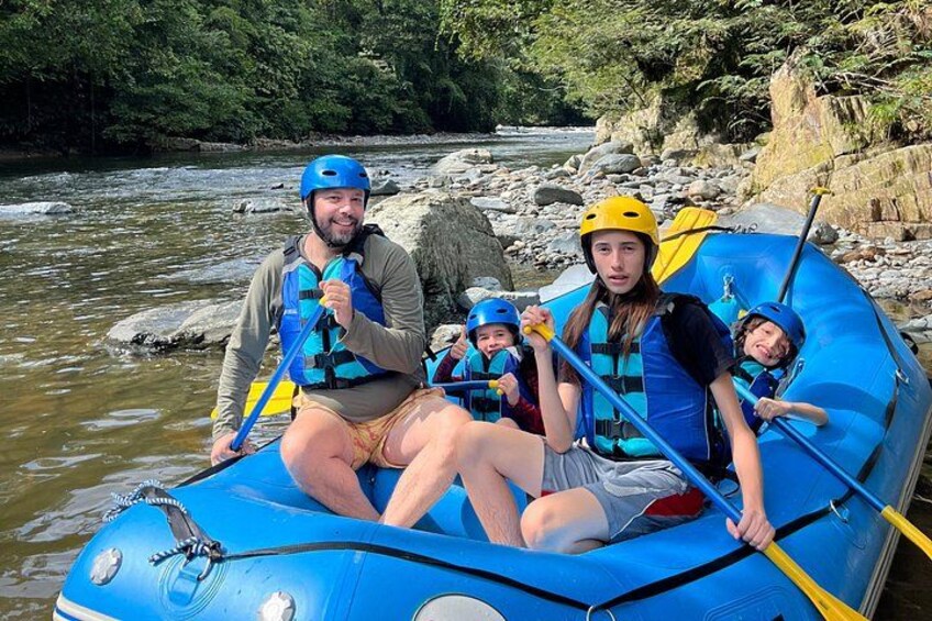 Un groupe de personnes se trouve dans un radeau gonflable bleu sur une rivière, entourée de rochers et de végétation. 4