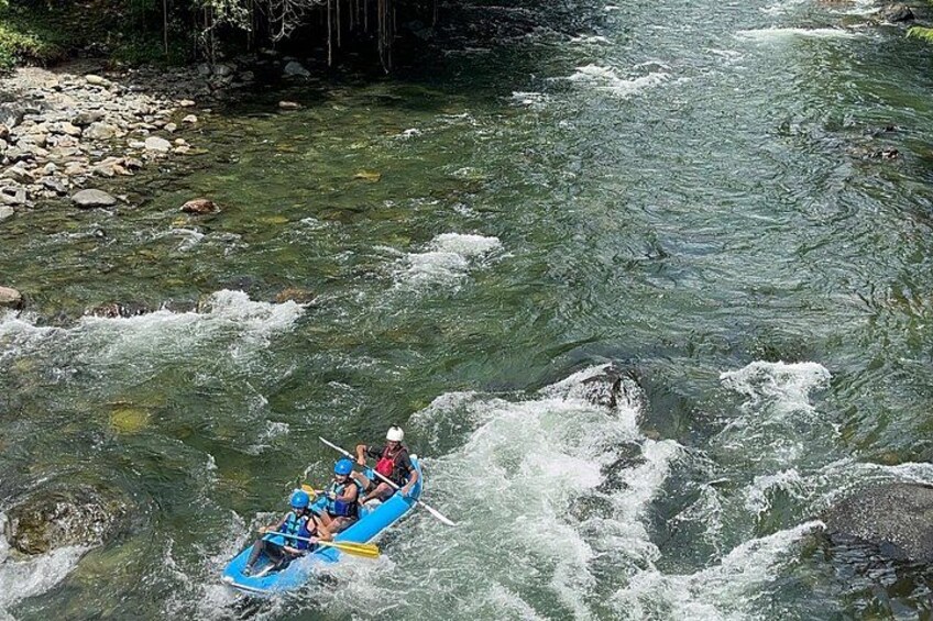 Un radeau bleu avec deux personnes à bord, naviguant sur une rivière aux courants rapides. 3