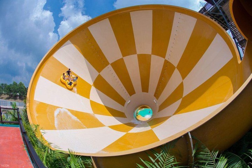 A large, yellow and white striped water slide with a person at the top. 3