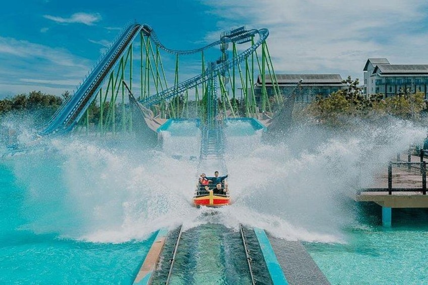 A water ride with a roller coaster structure, water splashing, and a clear blue sky. 1