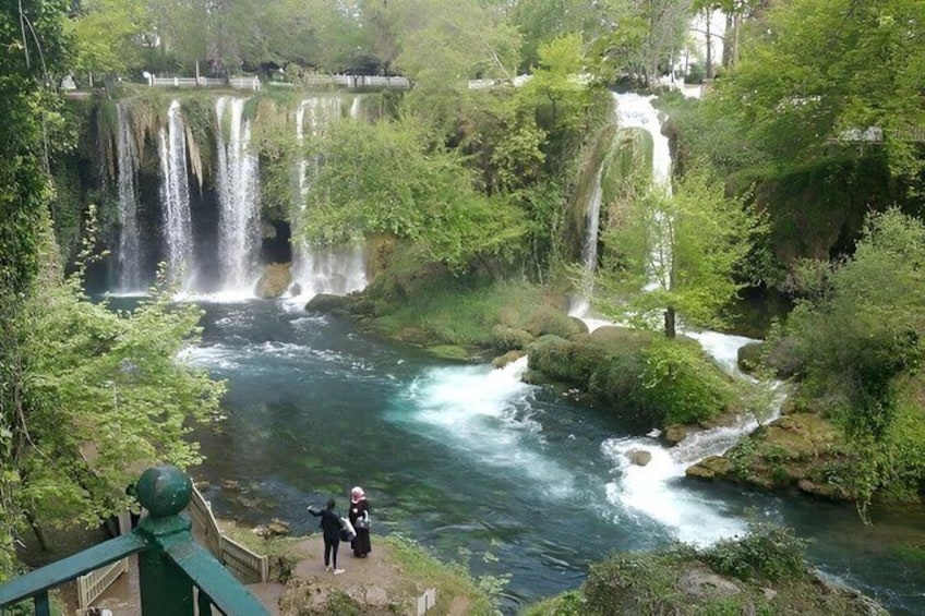 A waterfall cascading over rocks into a river surrounded by lush greenery. 4