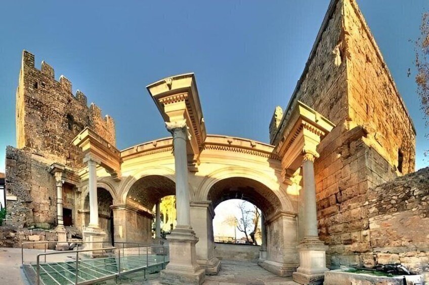 An ancient stone archway with columns, a stone wall, and a clear sky. 2