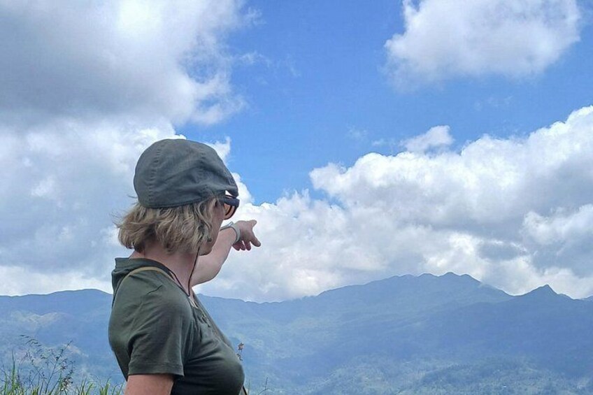 A person pointing at a mountain range under a partly cloudy sky. 3