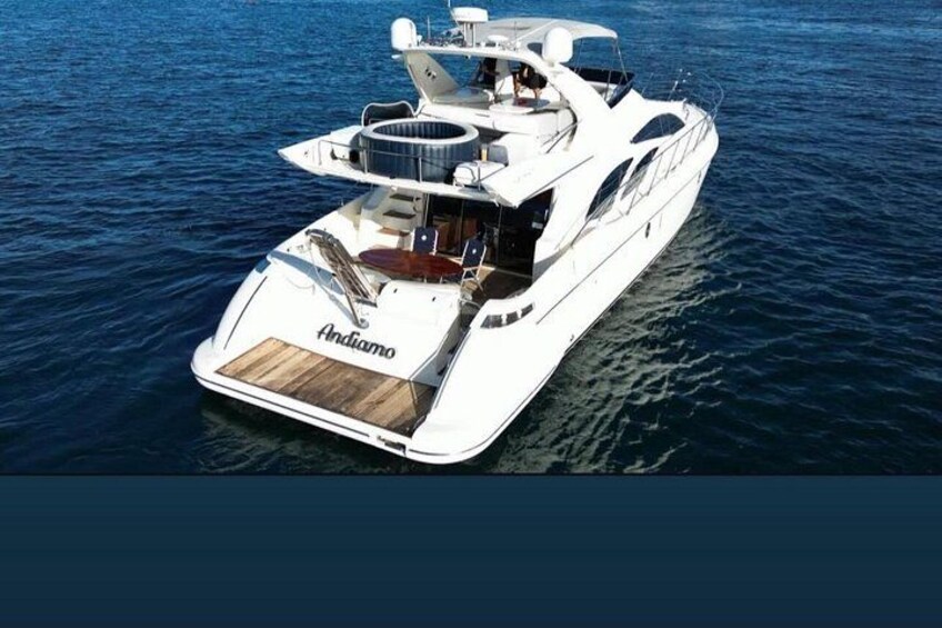 A white yacht with the name 'Andiamo' on the stern, sailing on calm waters. 1