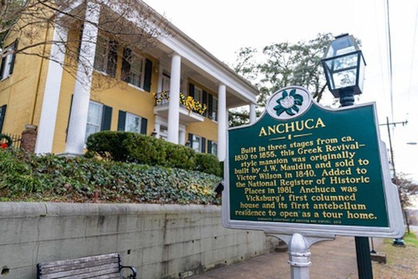 A historic house named Anchucca with a green signboard, a balcony, and a lamp post. 2
