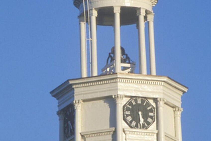 A clock tower with a statue on top, set against a clear blue sky. 4