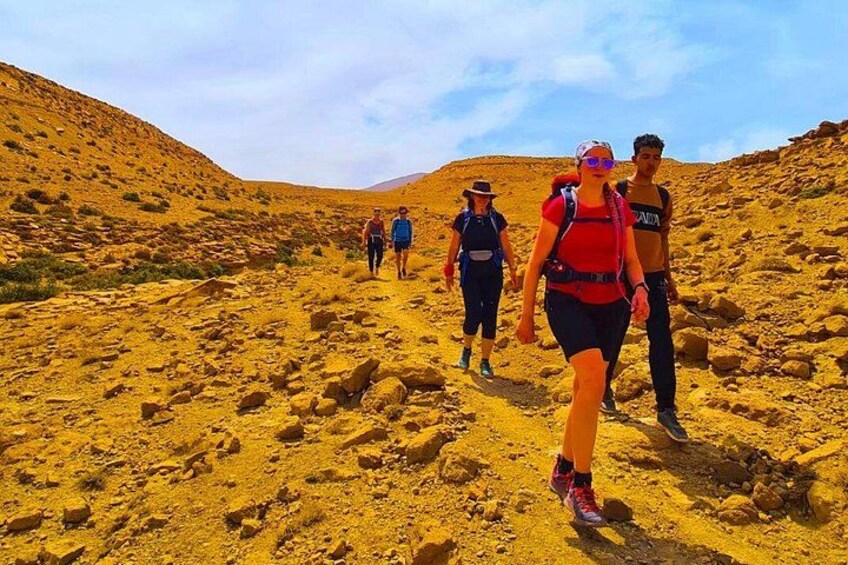 A group of hikers walking on a rocky trail in a desert landscape. 2
