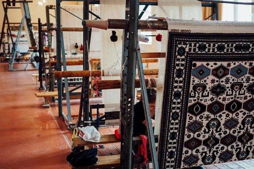 A textile workshop with looms and patterned rugs. 4