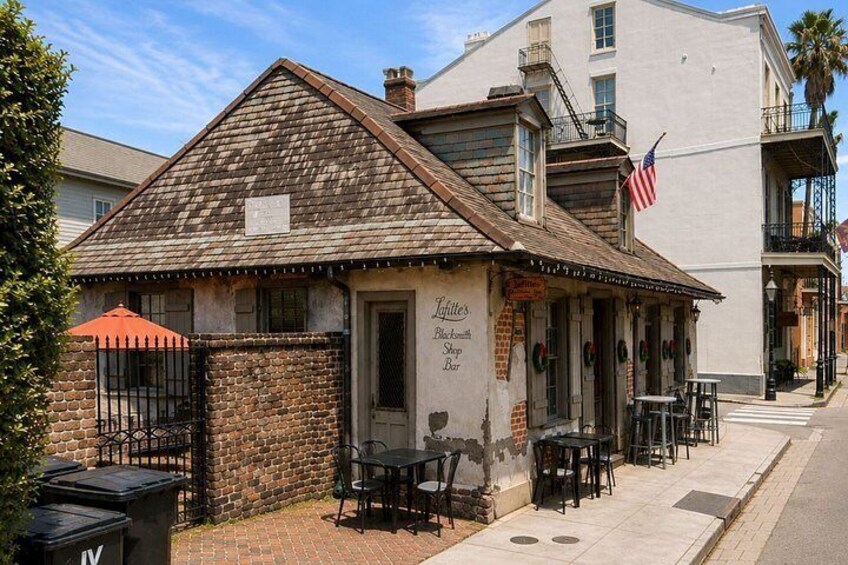 A rustic building with a brick facade, a wooden roof, and outdoor seating. 3