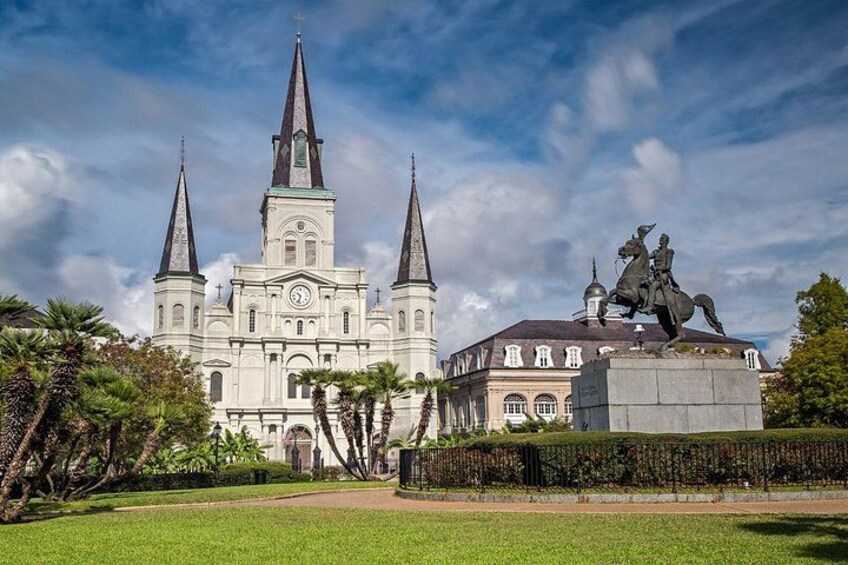 A large white church with three spires, a statue of a person on horseback, and a well-maintained lawn. 4