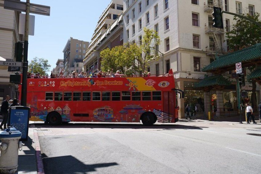 Un autobús de dos pisos rojo con 'CitySightseeing San Francisco' en la carrocería, circulando por una calle de la ciudad. 5