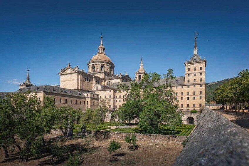 A large historic building with multiple domes and towers, surrounded by trees and a clear sky. 5