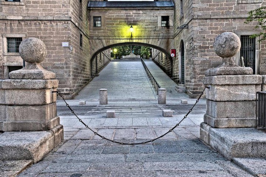 A stone bridge leading to a building with a yellow light at the end. 2