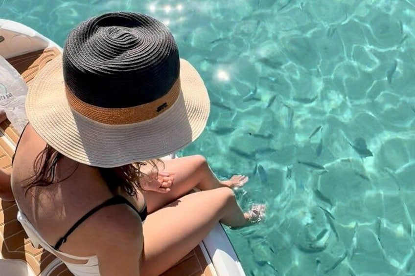 A person sitting by a pool with clear water, wearing a hat and a swimsuit. 2