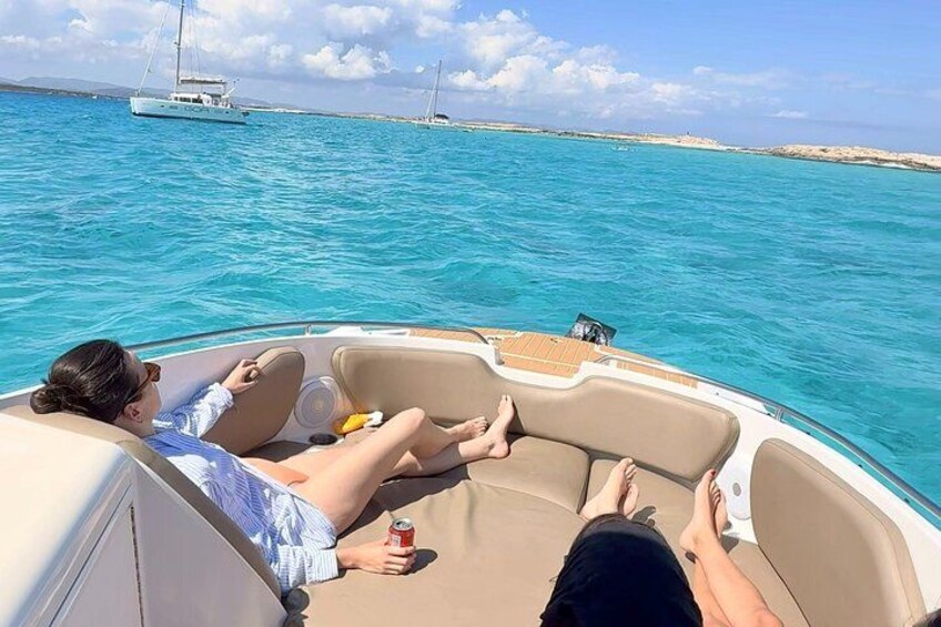 A boat with two people relaxing on the deck, surrounded by turquoise water and distant sailboats. 4
