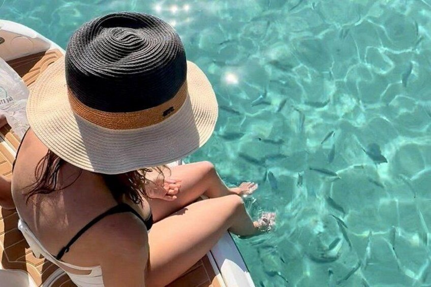A person sitting by a pool with clear water, wearing a hat and a swimsuit. 4