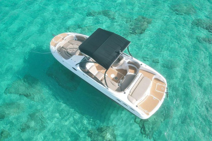 A boat with a canopy, clear turquoise water, and a sandy bottom. 3