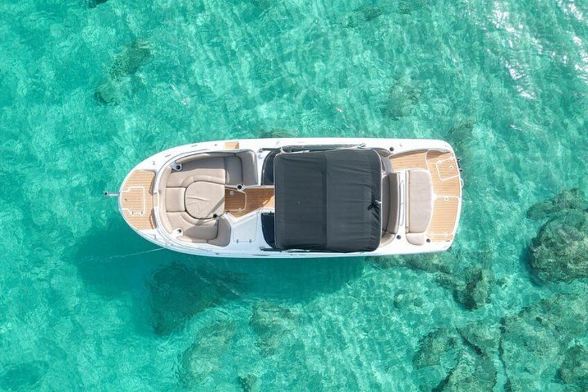 A boat on clear turquoise water with a rocky bottom. 1