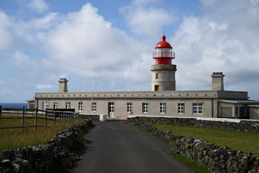 A lighthouse with a red top, a stone wall, and a clear sky. 5