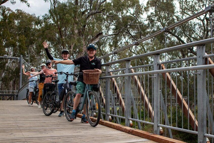 Un grupo de personas en bicicletas sobre un puente de madera con barandas metálicas. 2