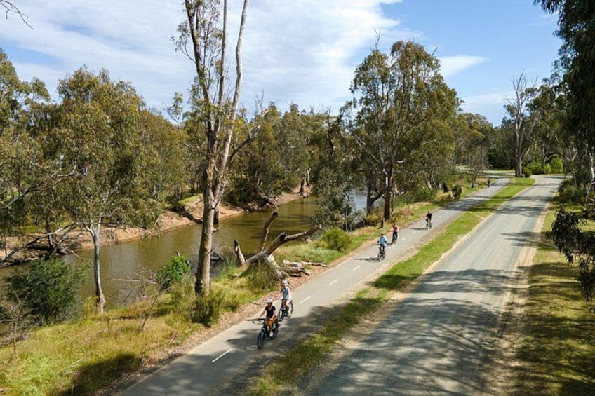 Un camino pavimentado junto a un río, con ciclistas. 5