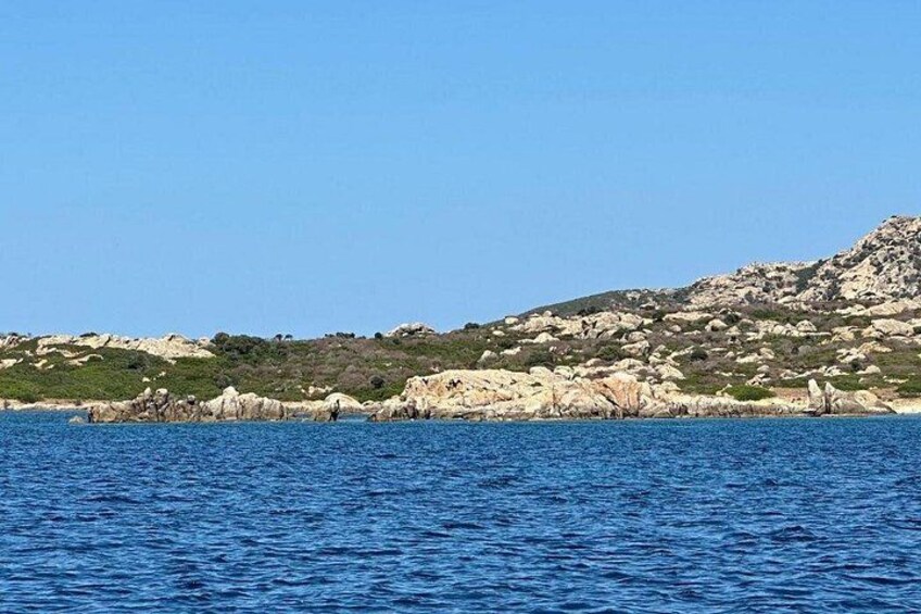 A coastal landscape with rocky terrain and clear blue water. 3